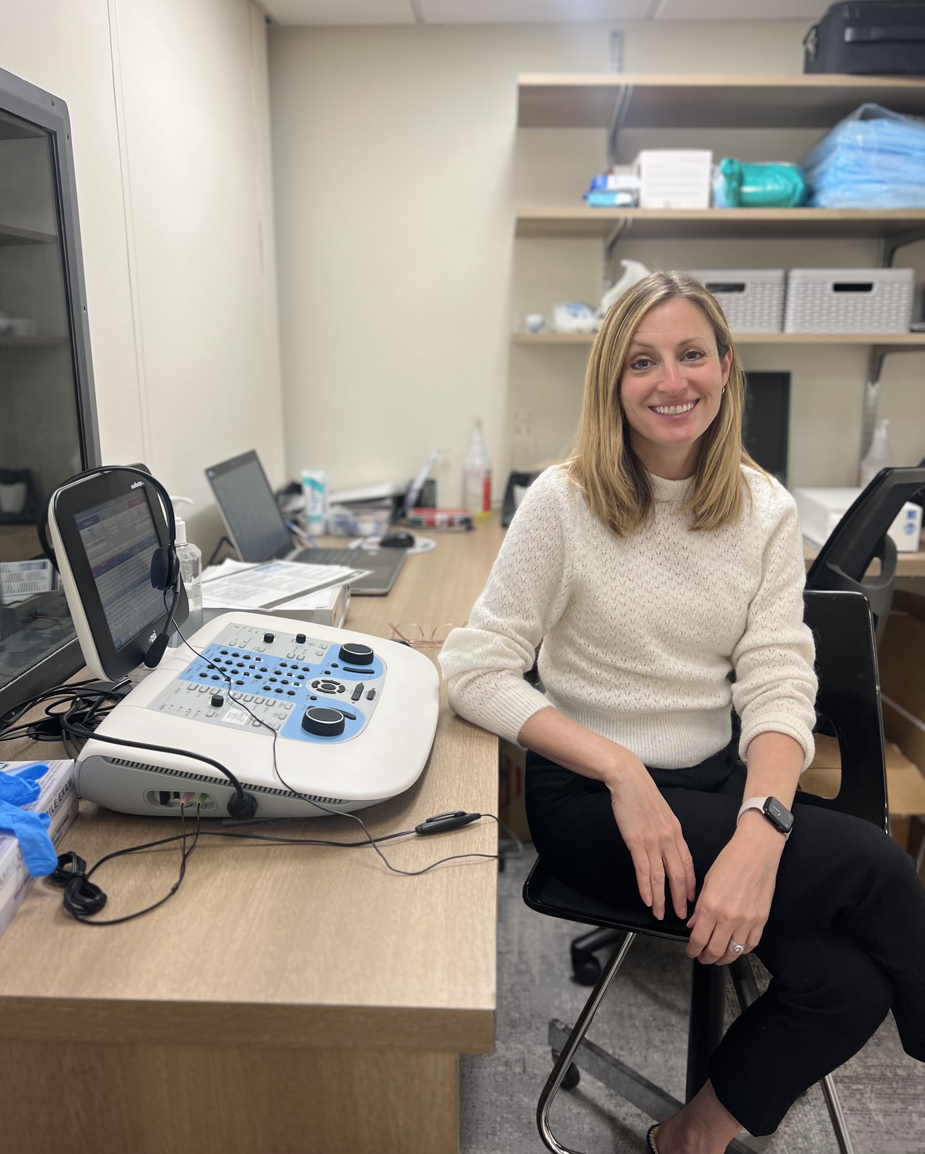 woman smiling next to an audiometer