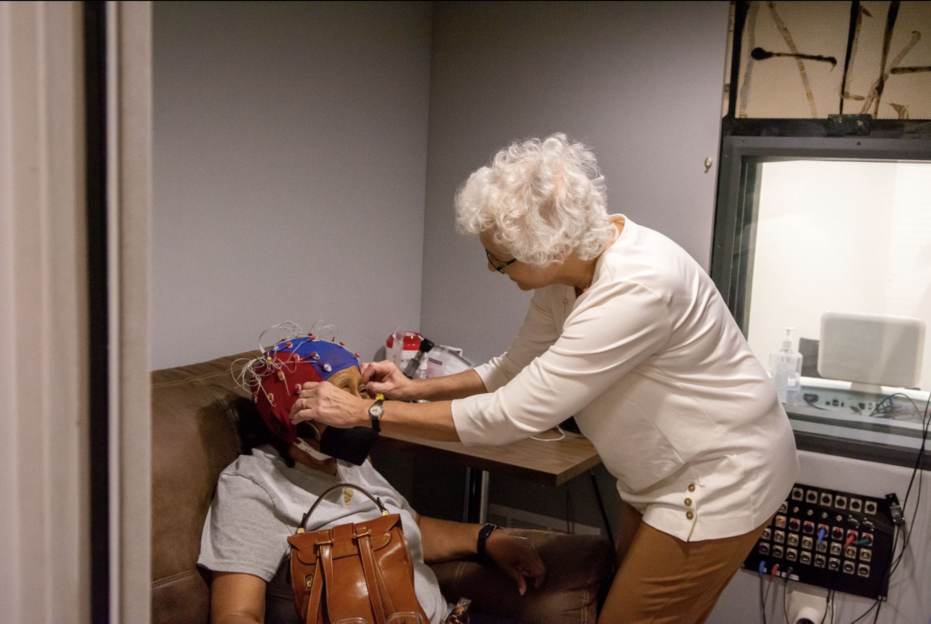 Woman putting an EEG cap on another woman's head